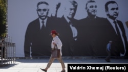 A pedestrian in Pristina walks past a banner depicting four Kosovo war crimes suspects, including former Kosovo President Hashim Thaci, who are standing trial in The Hague. 