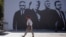 A pedestrian in Pristina walks past a banner depicting four Kosovo war crimes suspects, including former Kosovo President Hashim Thaci, who are standing trial in The Hague. 