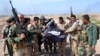 Iraqi Kurdish Peshmerga soldiers hold a flag belonging to the Islamic State militant group after they regained control of an area west of Kirkuk in March 2015.