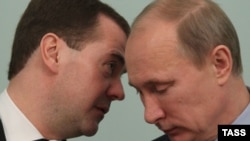 Президент России Дмитрий Медведев (слева) и премьер-министр России Владимир Путин шепчутся на заседании правительства. Москва, 27 декабря 2011 года.