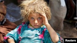 A Yazidi girl fleeing violence in the Iraqi town of Sinjar rests at the Iraqi-Syrian border crossing in mid-August.