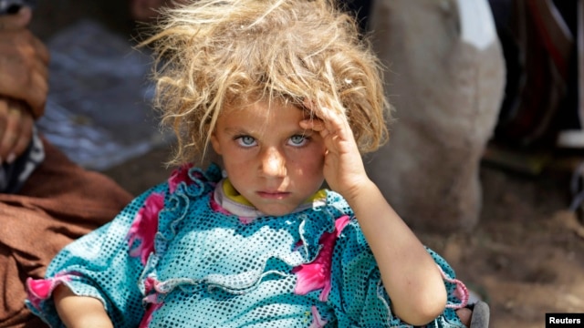 A Yazidi girl fleeing violence in the Iraqi town of Sinjar rests at the Iraqi-Syrian border crossing in mid-August.