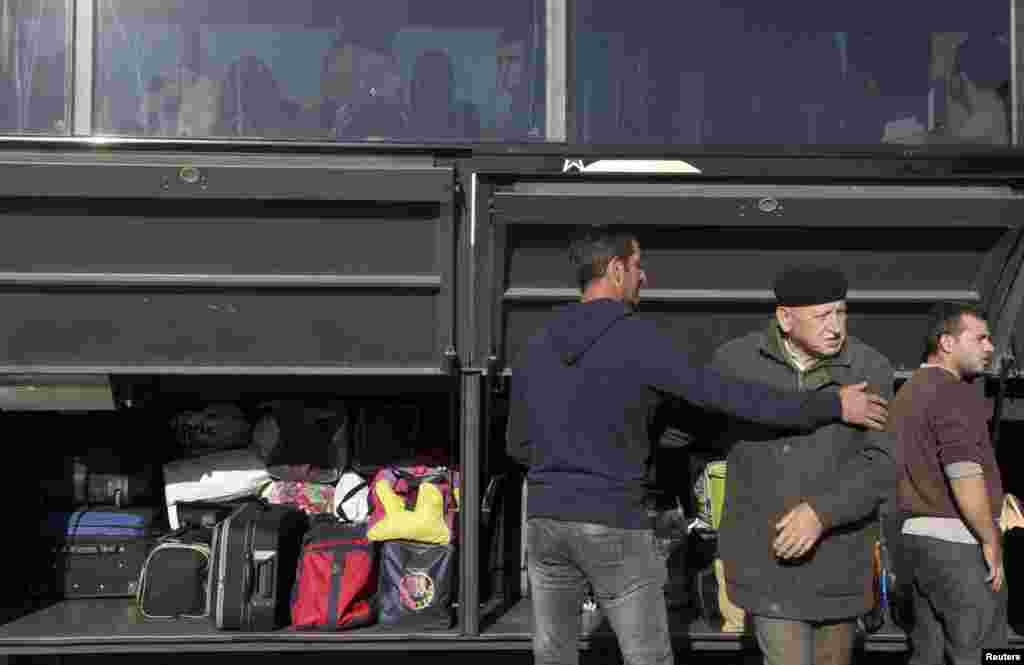 Passengers load their baggage into a bus.