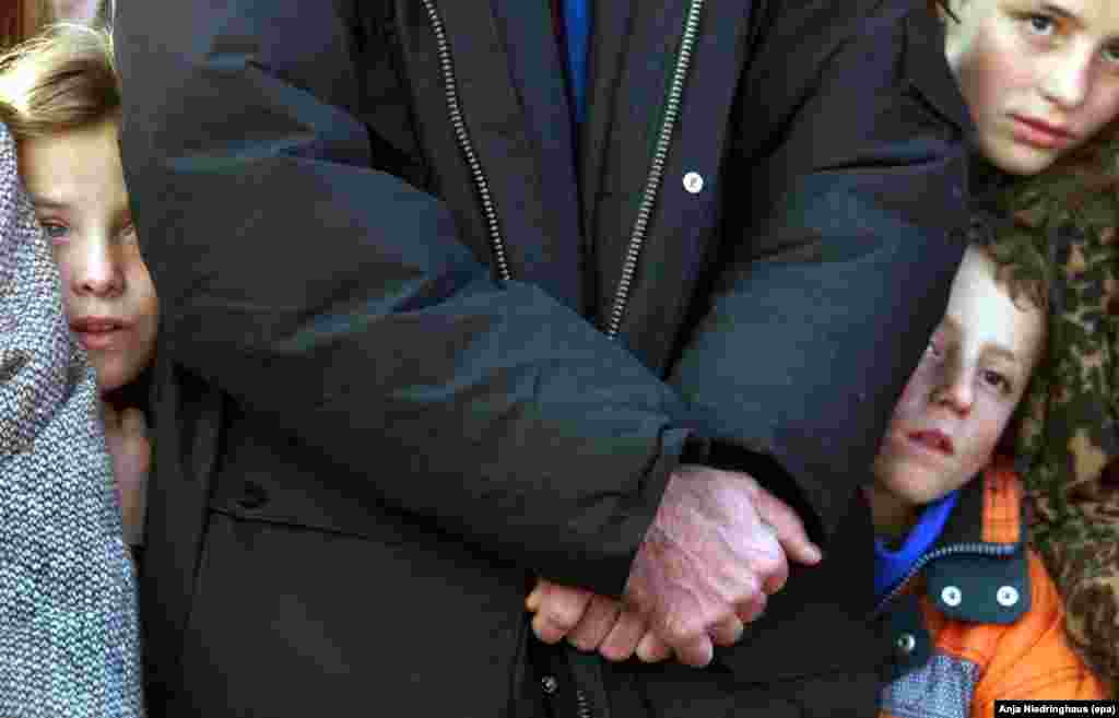 Kosovo Albanian children stand beside their father as they wait for humanitarian aid to arrive in the town of Pec, 80 kilometers west of Pristina, on November 30,1999.