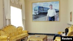 A woman relaxes underneath a photo of President Gurbanguly Berdymukhammedov at the resort of Avaza.