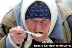 Люди едят в рамках благотворительной акции по раздаче еды среди малообеспеченных и бездомных людей во время снегопада в Ставрополе, 17 февраля 2021 года