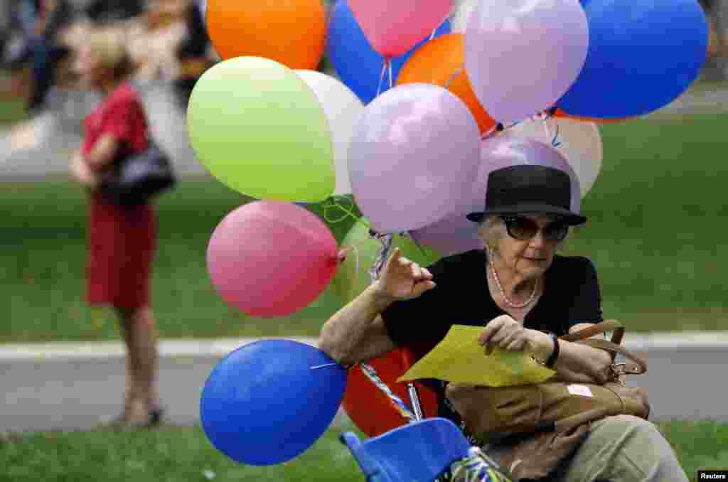 An activist sits on a bench holding onto multicolored balloons to mark International Day Against Homophobia and Transphobia in Belgrade. (AFP/Saul Loeb)