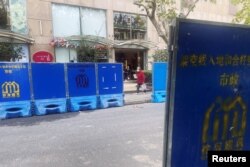 O femeie trece pe lângă barierele instalate de-a lungul unui drum unde au avut loc proteste față de restricțiile dure anti-Covid, în Shanghai, China, 28 noiembrie 2022.