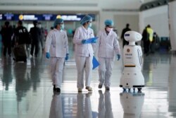 Ухань әуежайында кетіп бара жатқан медицина қызметкерлері және робот полицей. Қытай, 8 сәуір 2020 жыл.