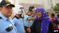 A relative of an inmate remonstrates with Turkish policemen standing guard outside Sanliurfa prison, where at least 13 prisoners died in a fire on June 17. 