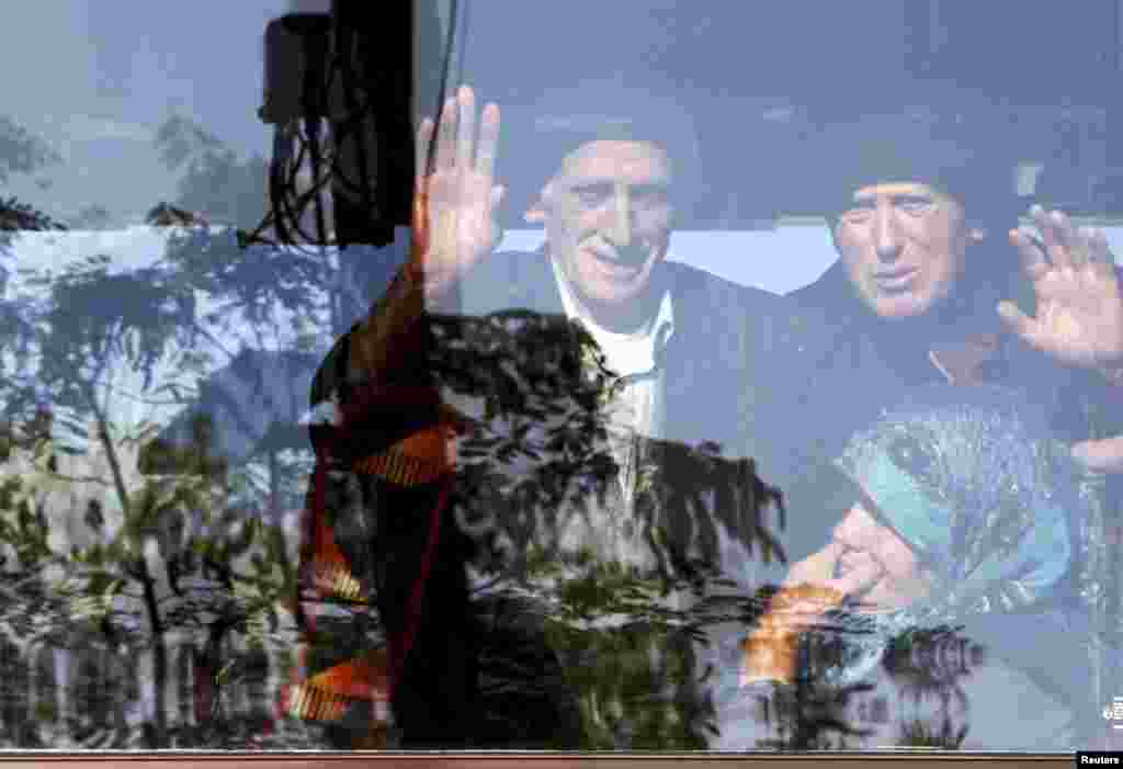 Ethnic Albanians wave from a bus window as they depart for the EU from the southern Serbian town of Presevo on October 20.