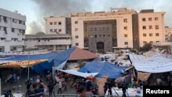 Клубы дыма поднимаются над районом города Газа, где расположен медицинский комплекс и центральная больница Аль-Шифа, возле которой укрываются палестинцы от бомбардировок, 8 ноября 2023 года