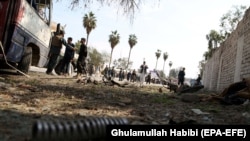 Afghan policemen inspect the scene after a deadly blast in Jalalabad on March 19. 