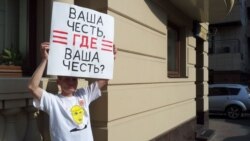 Активист держит плакат в поддержку участниц панк-группы Pussy Riot, обвиняемых в хулиганстве, перед зданием суда в Москве. 30 июля 2012 года.
