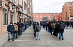 Рабочие-мигранты в защитных масках у центра миграционного контроля в Санкт-Петербурге.