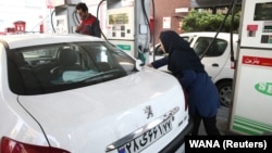 A woman fills up her tank at a gas station after a hike in fuel prices was announced in Tehran on November 15.