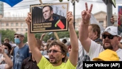 Un protestatar ține în mână imaginea lui Alexei Navalnîi, iar mesajul este că acesta a fost otrăvit și trebuie găsiți vinovații. Imagine din 22 august 2020