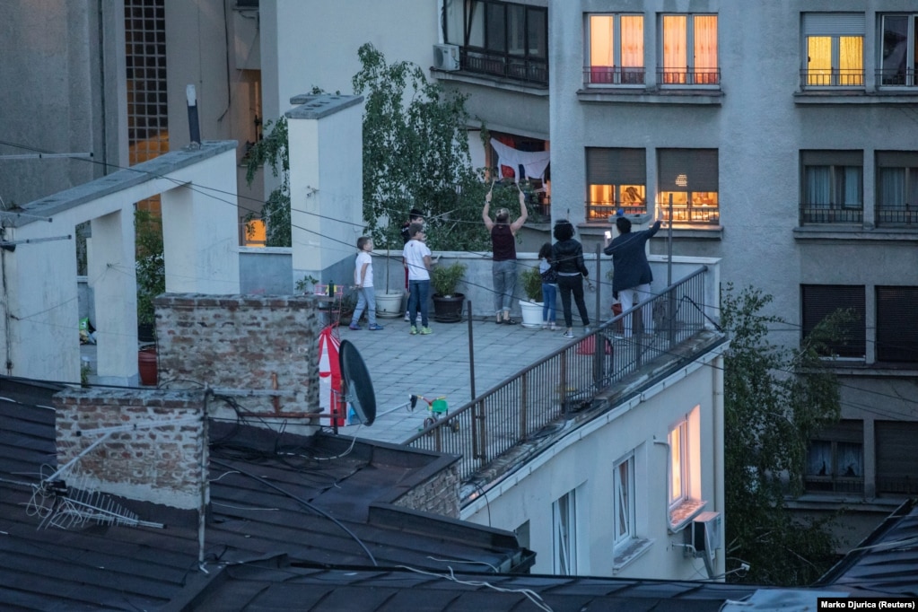Banorët e Beogradit bëjnë zhurmë ndërsa qëndrojnë në çatinë e një ndërtese gjatë një proteste më 1 maj. Ata kundërshtonin masat e izolimit të ndërmarra nga qeveria serbe.