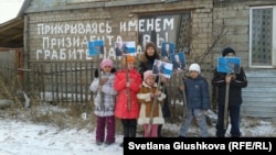 Дети, живущие в доме на окраине Астаны, стоят с фотографиями президента Казахстана Нурсултана Назарбаева, они просят власти не сносить их дом. 11 ноября 2013 года.