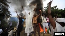 Sudanese demonstrators stand in front of the burning German Embassy in Khartoum after Friday Prayers on September 14.