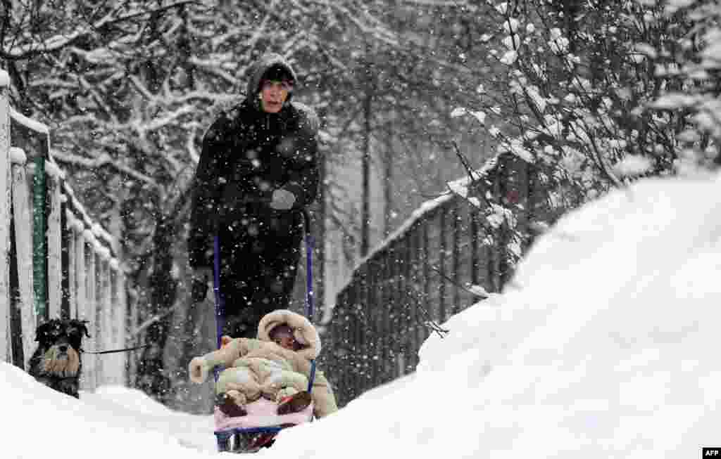 A woman walks with a child and dog in a snow-covered park in the Belarusian capital, Minsk. (AFP/Viktor Drachev)