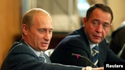 Russian President Vladimir Putin (L) gestures as Mass Media Minister Mikhail Lesin listens to him during a meeting with local press in the far eastern city of Vladivostok, August 24, 2002