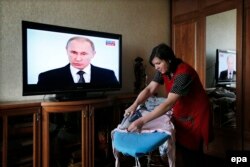Женщина гладит белье и слушает трансляцию послания президента России Владимира Путина. Москва, 4 декабря 2014 года.