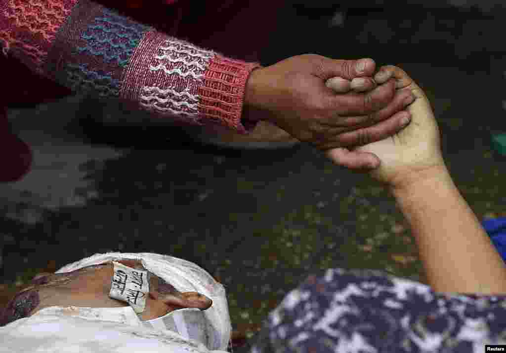 A woman holds the hand of a deceased relative who died during an earthquake outside a hospital in Kathmandu, Nepal. (Reuters/Adnan Abidi)