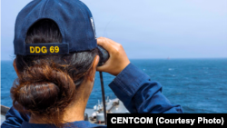 A US Sailor aboard the Milius stands watch as the guided-missile destroyer transits regional waters supporting the blockade against Iran.
