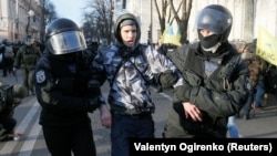 Ukrainian law enforcement officers detain a man following clashes with protesters on December 17 in Kyiv near parliament. 