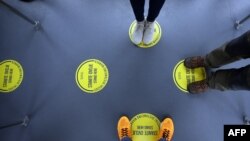 Pasagjerët në Aeroportin Ndërkombëtar të Zagrebit qëndrojnë mbi shenjat e vendosura në tokë, që kanë për qëllim ruajtjen e distancës mes njerëzve. 