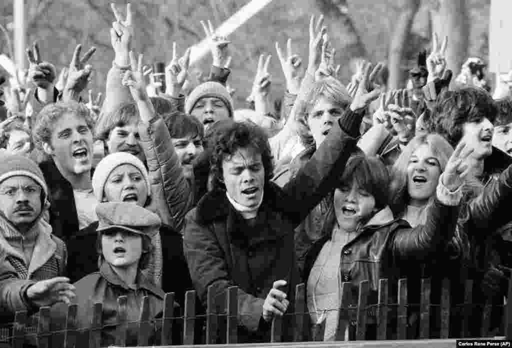 Fotografie din 14 decembrie 1980. Participanții la comemorarea lui John Lennon fac semnul păcii și cântă &bdquo;Give Peace A Chance&rdquo; în Central Park, New York.