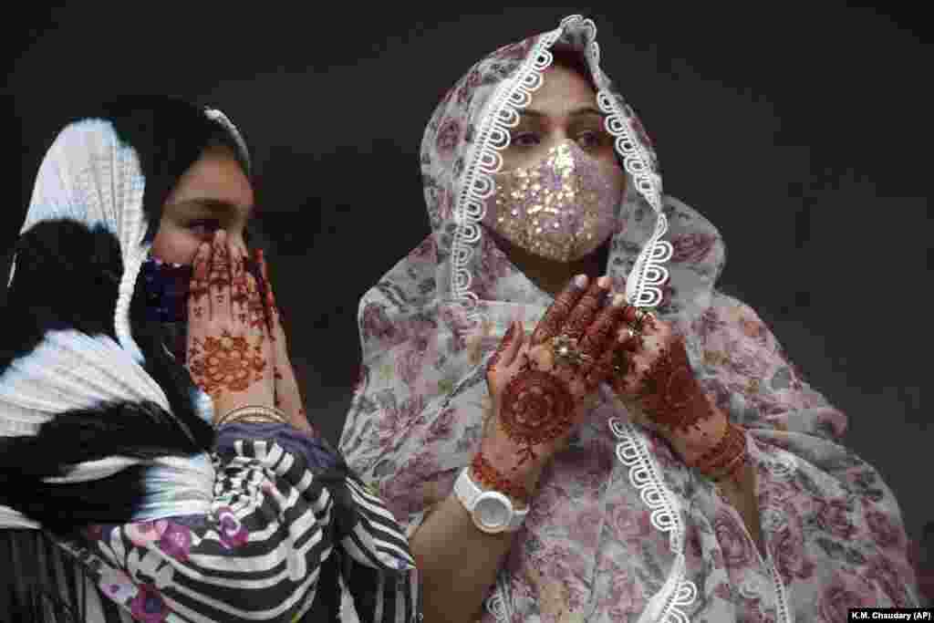 Muslim women with their hands painted with traditional henna at a mosque in Lahore, Pakistan