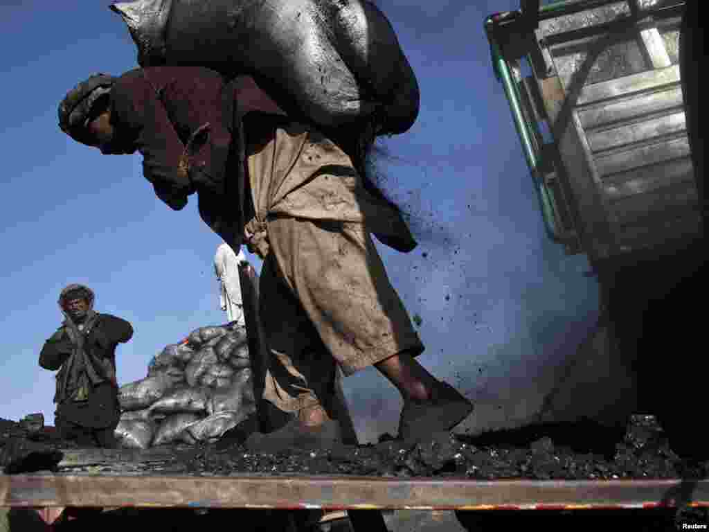 A laborer carries a sack of coal at a coal dumpsite outside Kabul. (Ahmad Masood for Reuters)