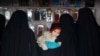 Жінка тримає дитину в магазині табору Аль-Хол, Сирія. 8 січня 2020 року