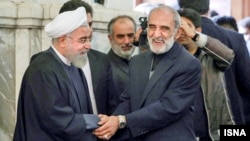 President Hassan Rouhani and conservative figure Hossein Shariatmadari greet each other. undated.