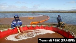 Workers fill a tank for collecting oil-water mixture from the water surface at the site of the spill into the Ambarnaya River outside Norilsk on June 7.