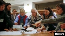 Election commission members count ballots after local elections at a polling station in Kyiv on October 25