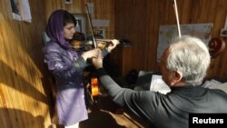 A teacher adjusts a student's violin work at the Kabul Music Academy.