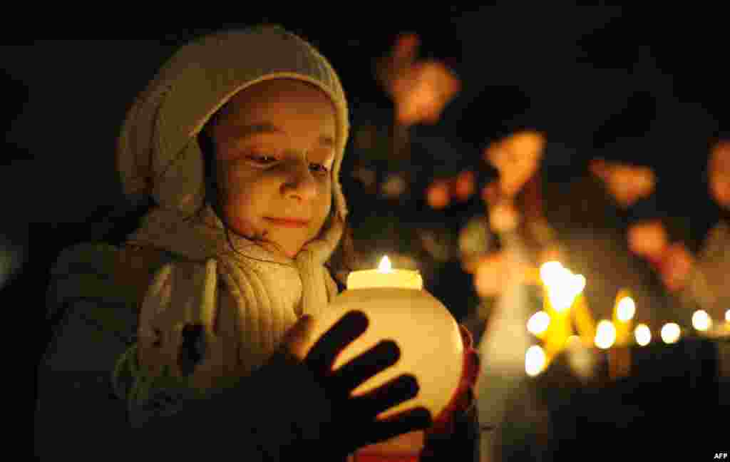 In Armenia, a young girl holds a candle outside Saint Gregory the Illuminator church in the Armenian capital, Yerevan, during an Armenian Orthodox church service on January 5, 2014