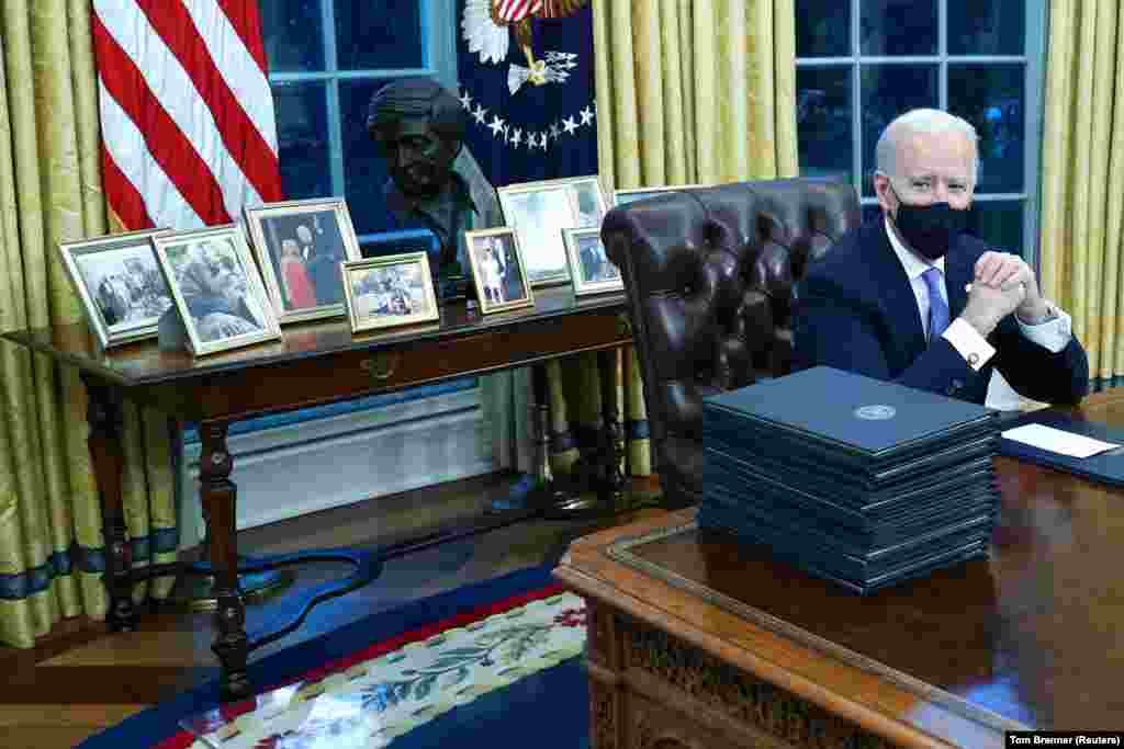 Az elnök azonnal munkához látott beiktatása után. Ezen a képen is éppen több dokumentumot készül aláírni az úgynevezett &quot;Resolute Desk&quot; mellett.