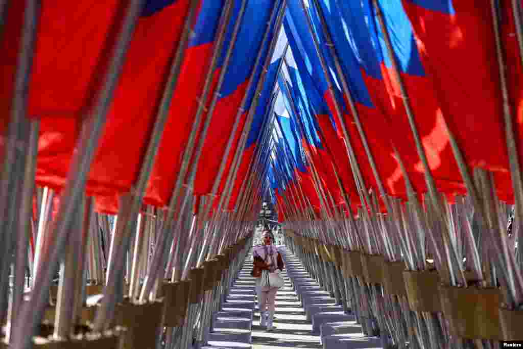 A woman walks amid a display of Russian state flags installed on a square in central Moscow on February 24, the third anniversary of Russia's full-scale invasion of Ukraine. 