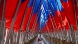 <p>A woman walks amid a display of Russian state flags installed on a square in central Moscow on February 24, the third anniversary of Russia's full-scale invasion of Ukraine. 