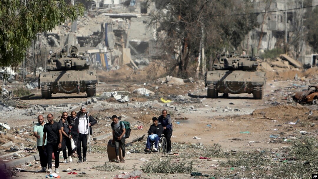 Un grup de palestinieni se evacuează din nordul Fâșiei Gaza, cu tancuri israeliene în urma lor, pe drumul Salah al-Din, pe 24 noiembrie 2023. Agențiile umanitare trag un nou semnal de alarmă cu privire la situația umanitară.