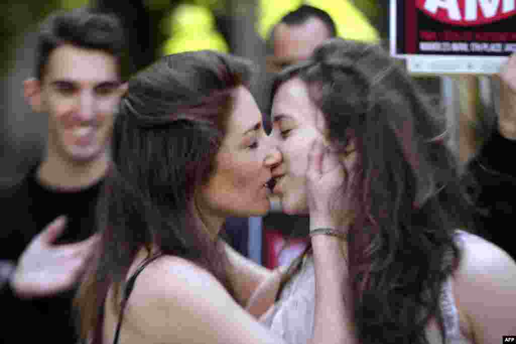 Two women kiss during a rally in support of gay marriage outside the French lower house, the National Assembly, in Paris. The National Assembly adopted a bill legalizing same-sex marriages and adoptions for gay couples, defying months of opposition protests. (AFP/Kenzo Tribouillard)