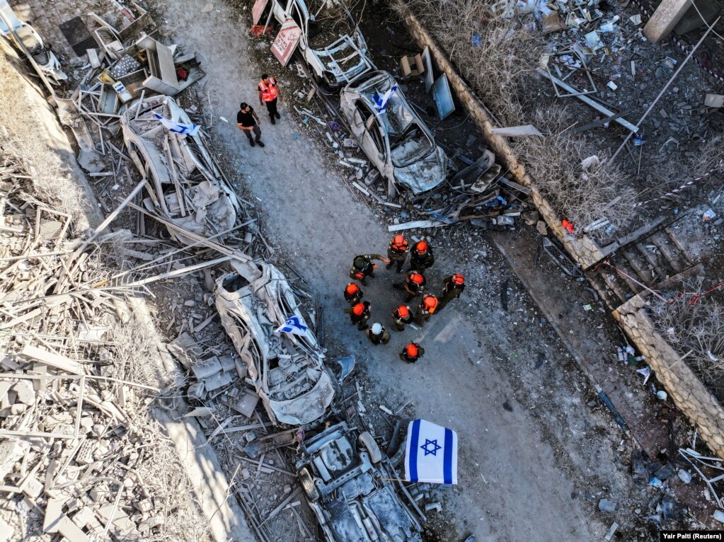 Fotografi e bërë me dron që shfaq forcat e shpëtimit pranë shtëpive të banimit, që u goditën nga një sulm raketor nga Irani, në Ramat Gan, më 14 qershor.
