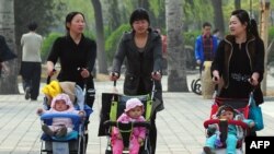 Китайские женщины гуляют с детьми в парке в Пекине.