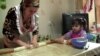 Shahnoz Komilzoda preparing food with her child in their kitchen in Dushanbe