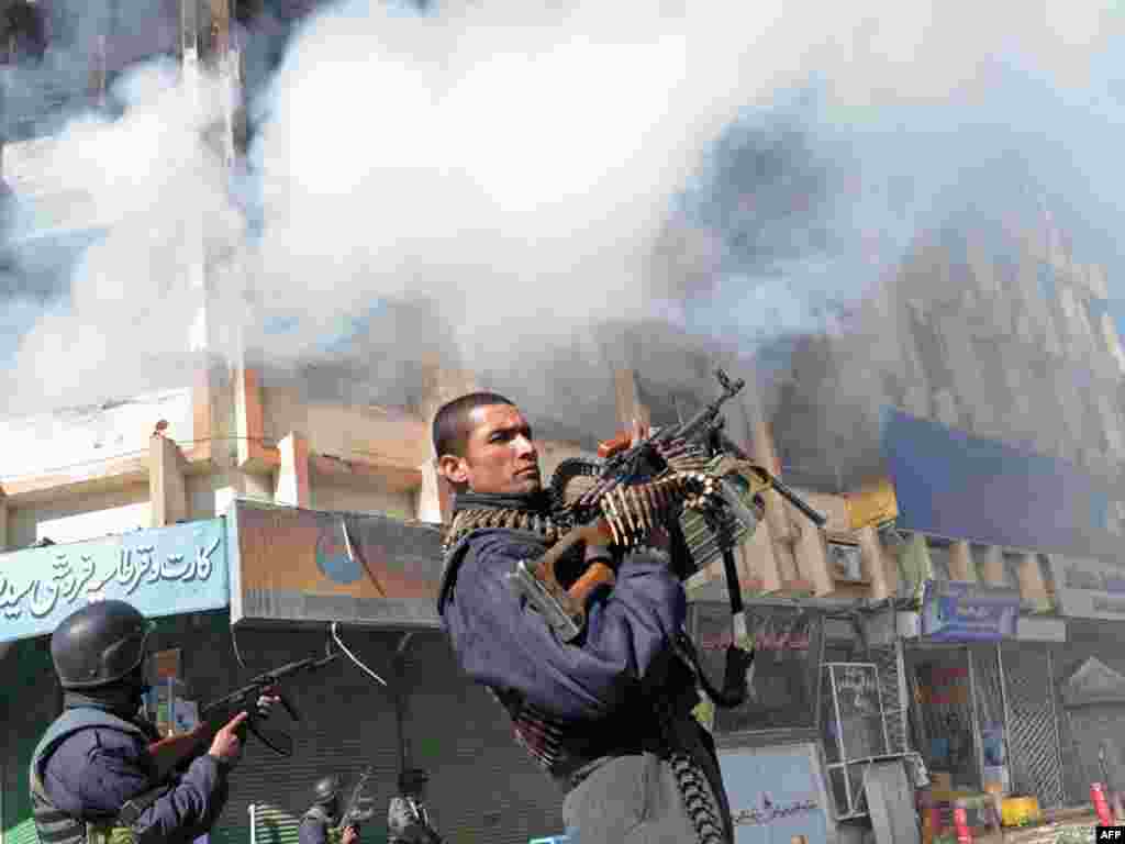 Afghan policemen stand guard near a burning market building after deadly clashes in Kabul. - Taliban militants launched a series of attacks in the capital on January 18, sparking gunbattles with security forces and leaving at least 12 dead. Photo by Massoud Hossaini for AFP