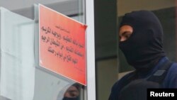 Germany - A German special police member looks at the banner on the door of a mosque association property in Berlin, Germany September 22, 2015